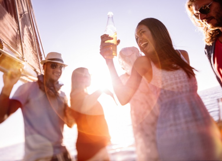 friends drinking beer and dancing on the beach