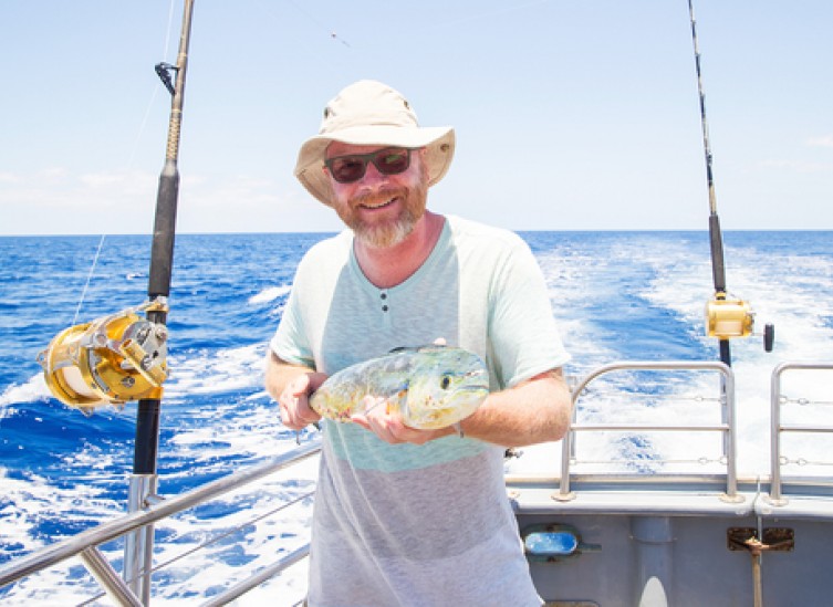 man holding fresh caught mahi mahi on ocean boat