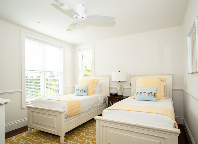 Room with two twin beds with yellow linens & ceiling fan
