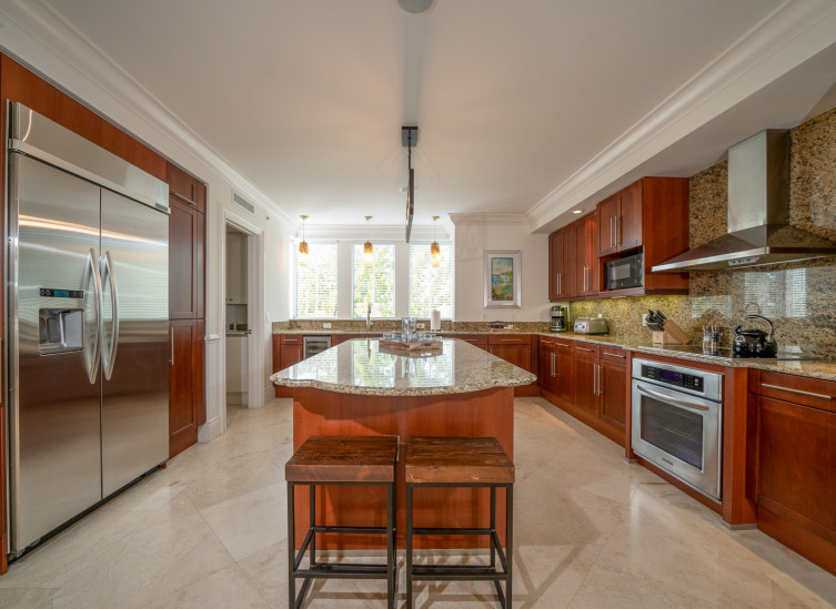 Full kitchen with wooden cabinets, kitchen island & steel appliances
