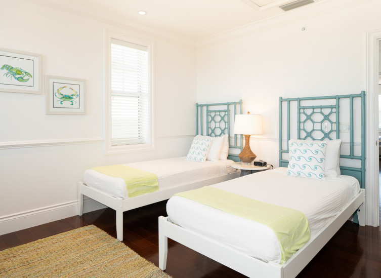 room with two twin beds with colorful pillows & jute rug