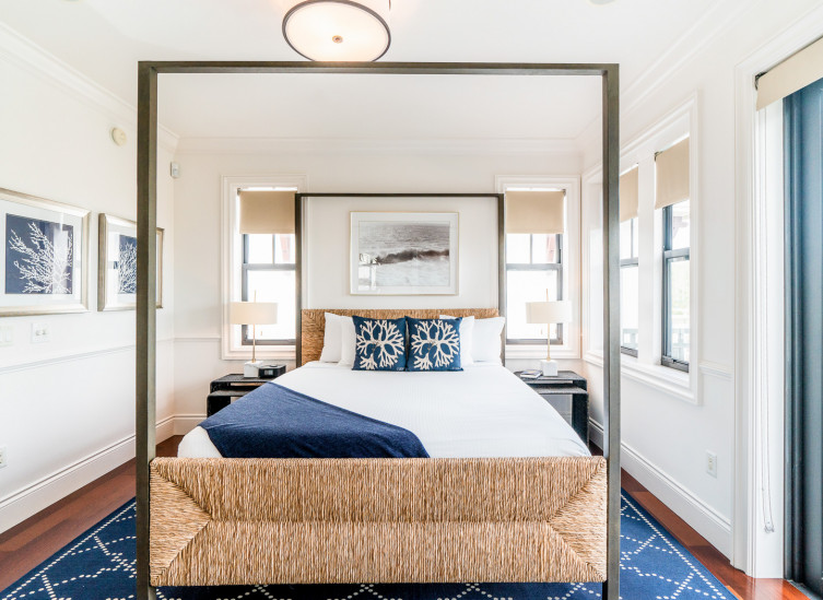 Room with double bed, wicker metal bed frame, blue rug & balcony door