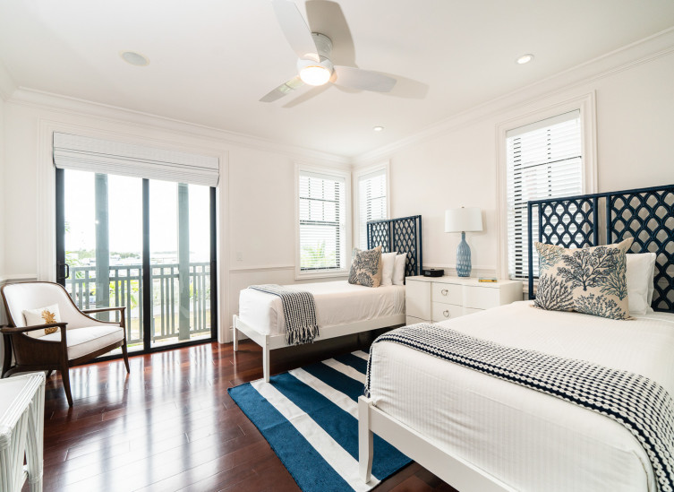 Room with two twin beds, striped rug in between them & white furniture