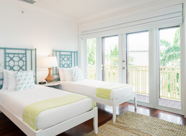 Room with two twin beds with aqua bed frames and door leading to balcony