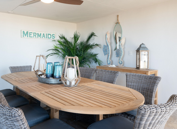 Outdoor shaded seating with long wooden table and eight wicker chairs
