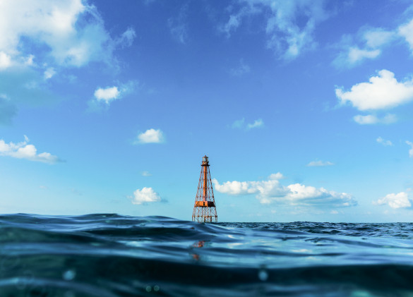 a red buoy in ocean water against a cloudy blue sky