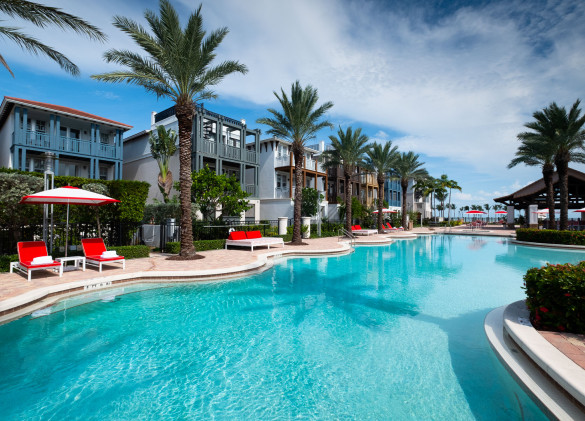 pool area with crystal blue water and palm trees with vacation homes in background