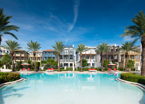 wide view of resort pool area lined with palm trees and vacation homes in background