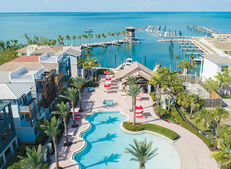 aerial view of property with vacation rentals and pool with boat slips and ocean in background