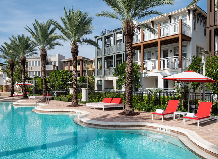 pool surrounded by palm trees with residences in background