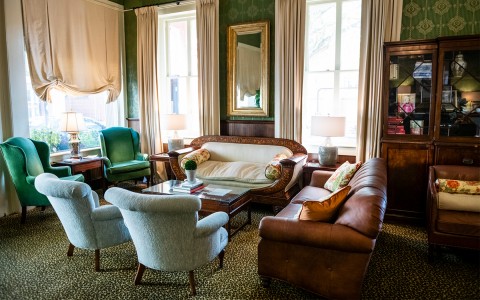 A living room with brown couches and green chairs.