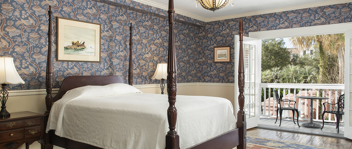 A large bed in a room with wallpaper and small artwork on the walls.
