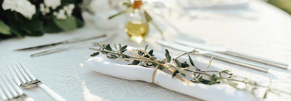 A white linen table with silverware small flowers.