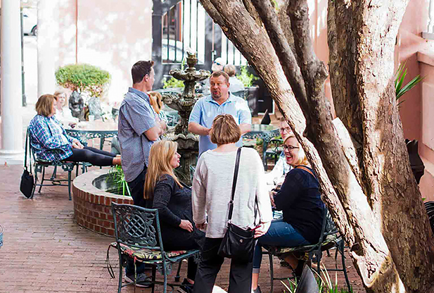 A group of people talking in an outdoor area next to a fountain.