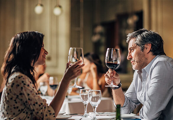 a man and a woman at dinner with wine glasses