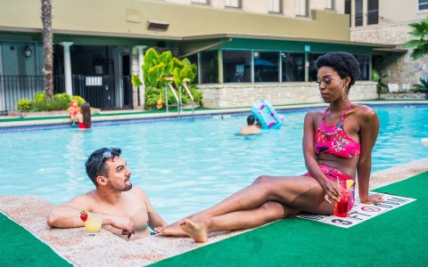 Man inside pool and woman sitting outside of it
