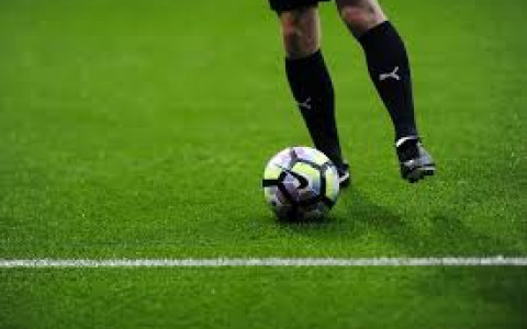 Players legs driblling a soccer ball on an empty field
