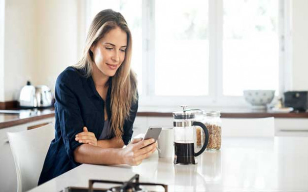 Young woman on her phone while enjoying a cup of coffee
