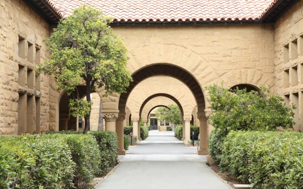 courtyard archways of stone building flanked by trees and bushes