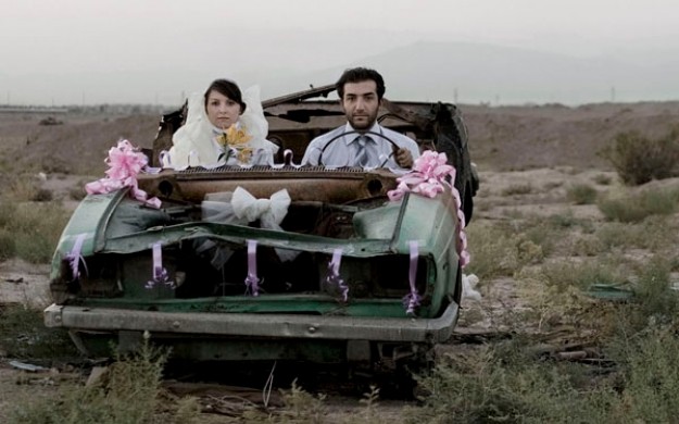 bride and groom sitting in dilapidated car decorated for a wedding