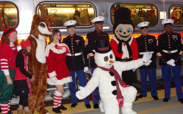 Soldiers in full formal garb posing for a photo with christmas mascots