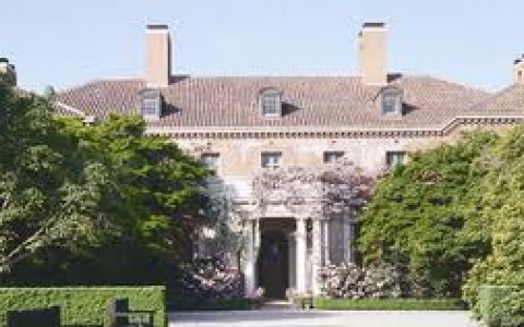 exterior of castle like mansion with stone facade and foliage surrounding door