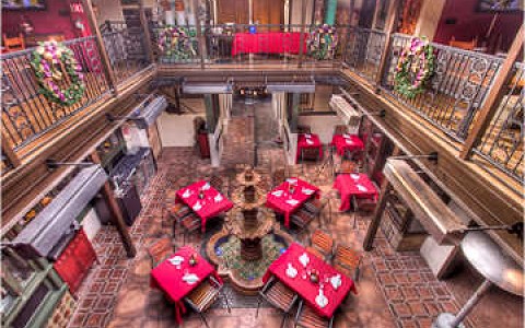 inside of Parisian style 2 story cafe. Tables dressed for the holidays with read table clothes and wreaths hanging