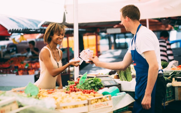 women and merchant exchanging money for goos at a farmers market
