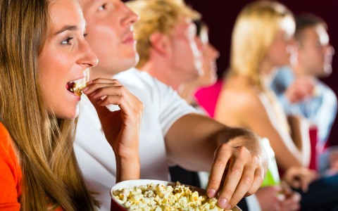 movie theater audience eating popcorn, enjoying the movie