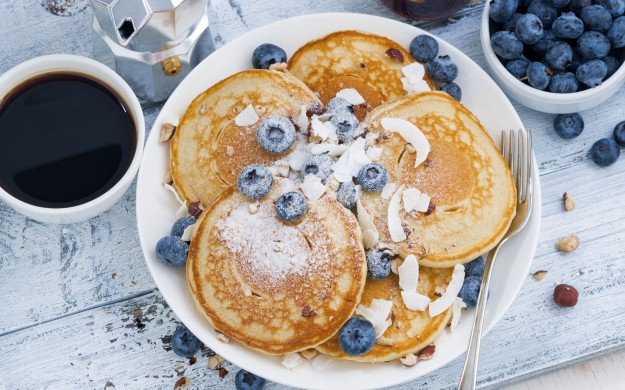 plate of blueberry pancakes and black coffee