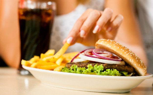 plate of burger and fries and a soda pop being picked at by a women
