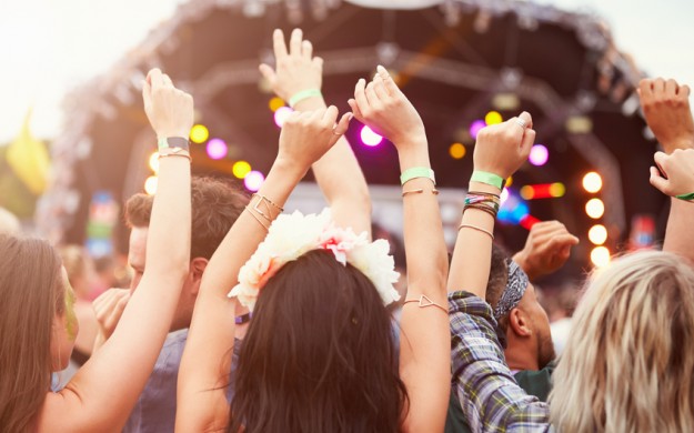 crowd at outdoor music festival with their hands up
