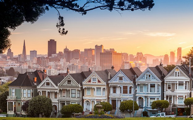 painted ladies houses line a street during sunset