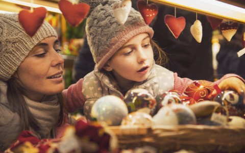 mother and daughter selecting ornaments at christmas market