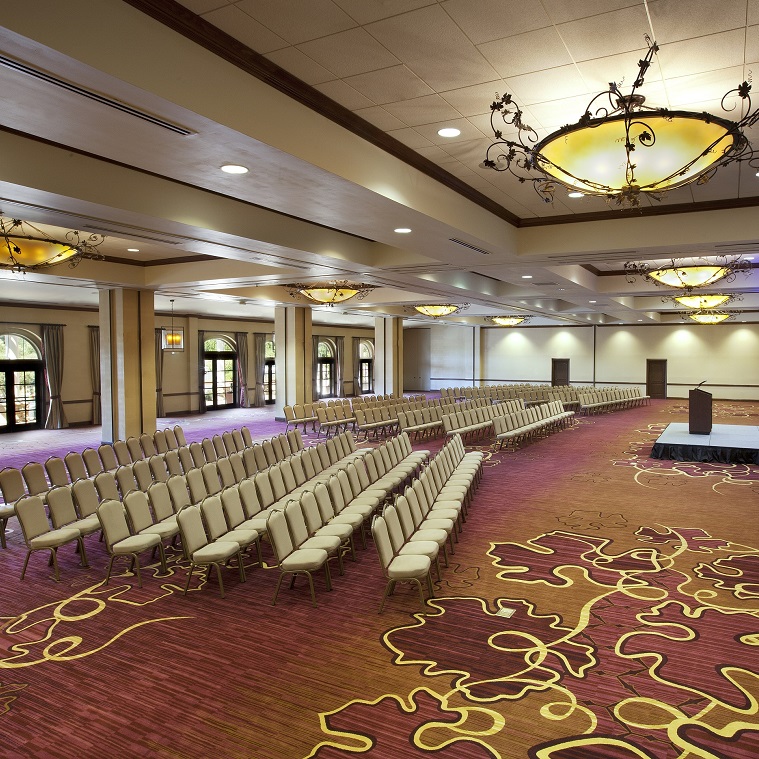 Large ball rooms with beige chairs and a red patterned carpet