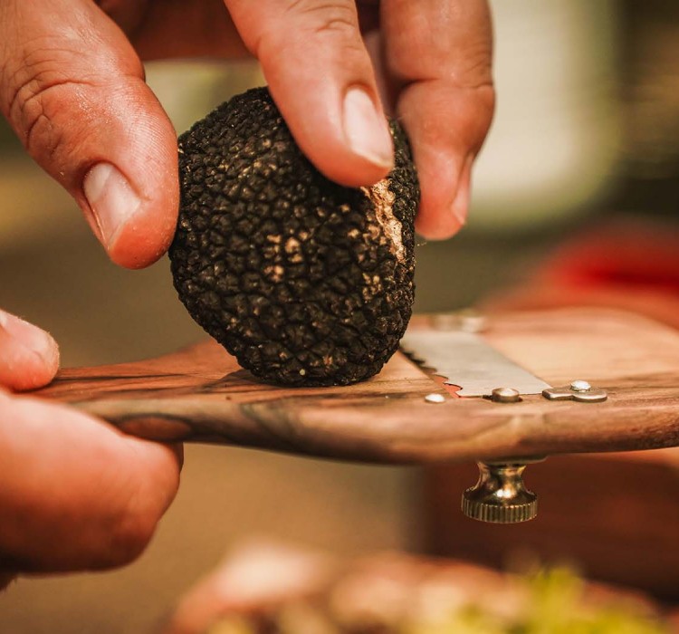 close up of a chef grating a truffle over a dish