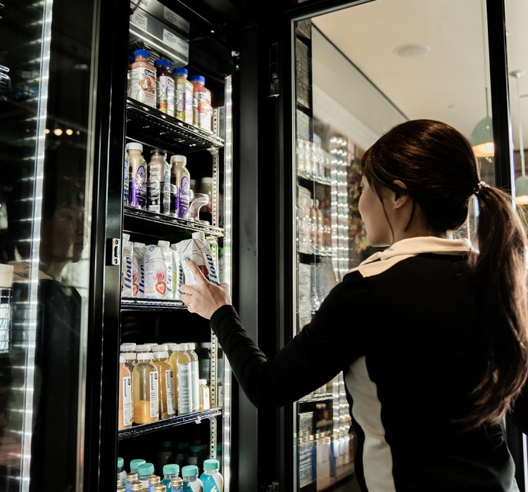 Woman opening a fridge and picking a beverage 