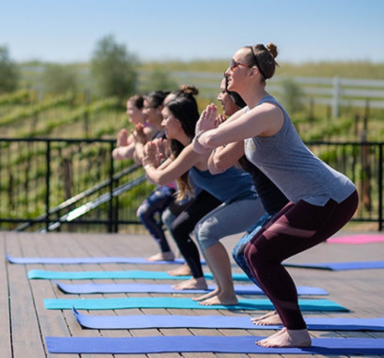 young women lined up doing a yoga pose at an outdoor yoga class on the patio at Meritage