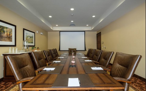 Conference room with a long wood table and leather chairs 