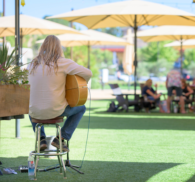 people enjoying an outdoor concert of a man playing an acoustic guitar