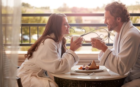Young couple having coffee together at their balcony