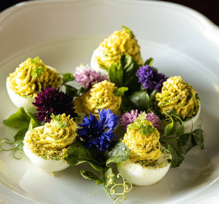deviled eggs on a plate with flower garnishes 