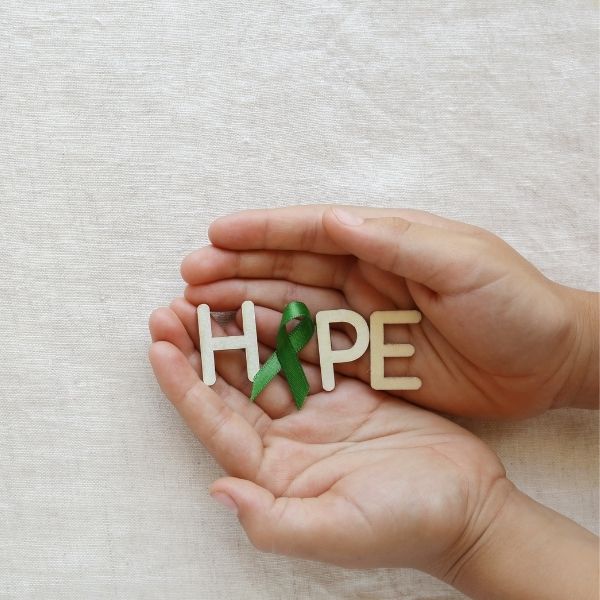 A person holding wooden letters that spell hope