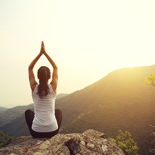 Woman doing yoga on top of a mountain