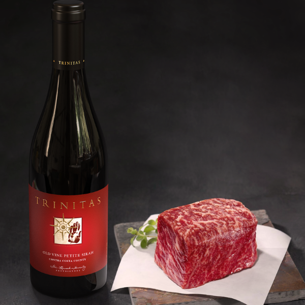 A large piece of steak with a wine bottle next to it