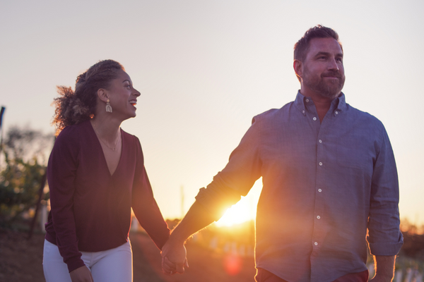 a couple holds hands at sunset