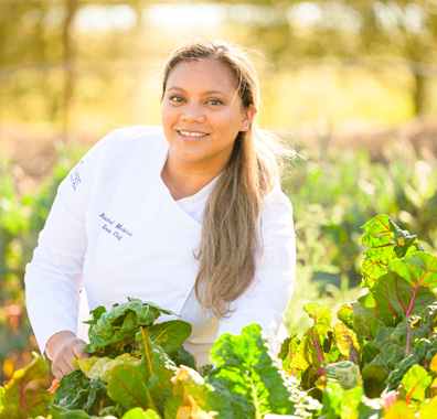 Meritage culinary team member picking fresh leafy vegetables from the garden