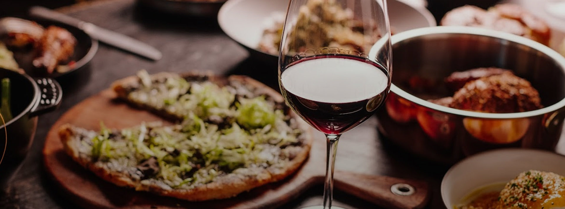 Glass of red wine with pizza and pasta in the background