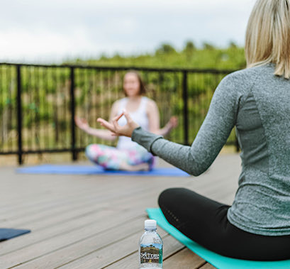 Two women doing a yoga pose on a deck