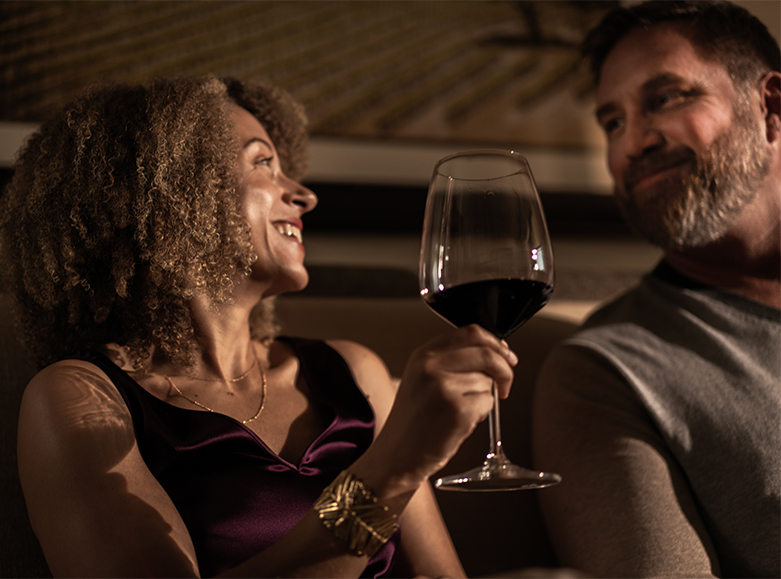 a woman enjoying a glass of red wine laughing with her companion